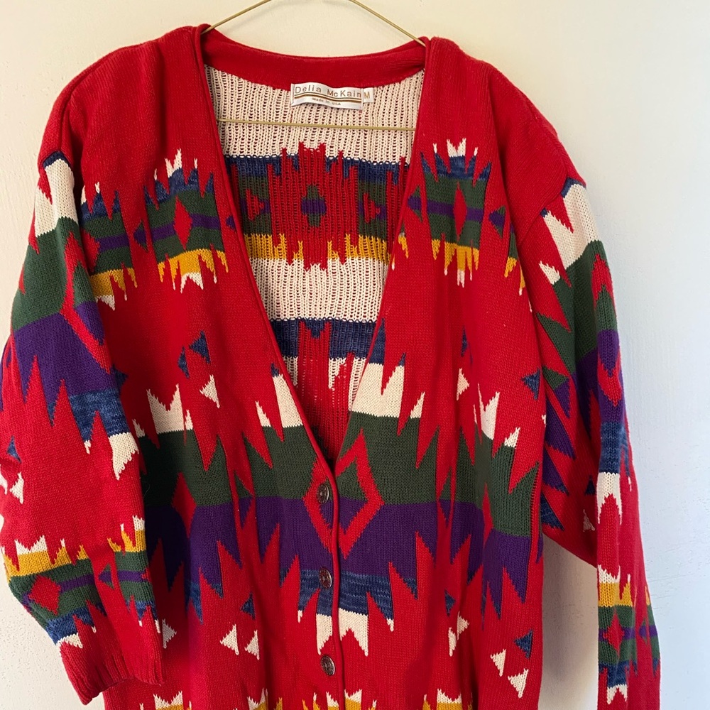 A Southwestern style sweater jacket with 5 silver colored buttons.